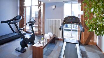Un gimnasio con equipamiento de ejercicio, un reloj y una ventana con vistas.