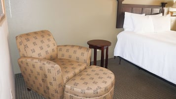 A hotel room with a bed, a chair, and a small table.
