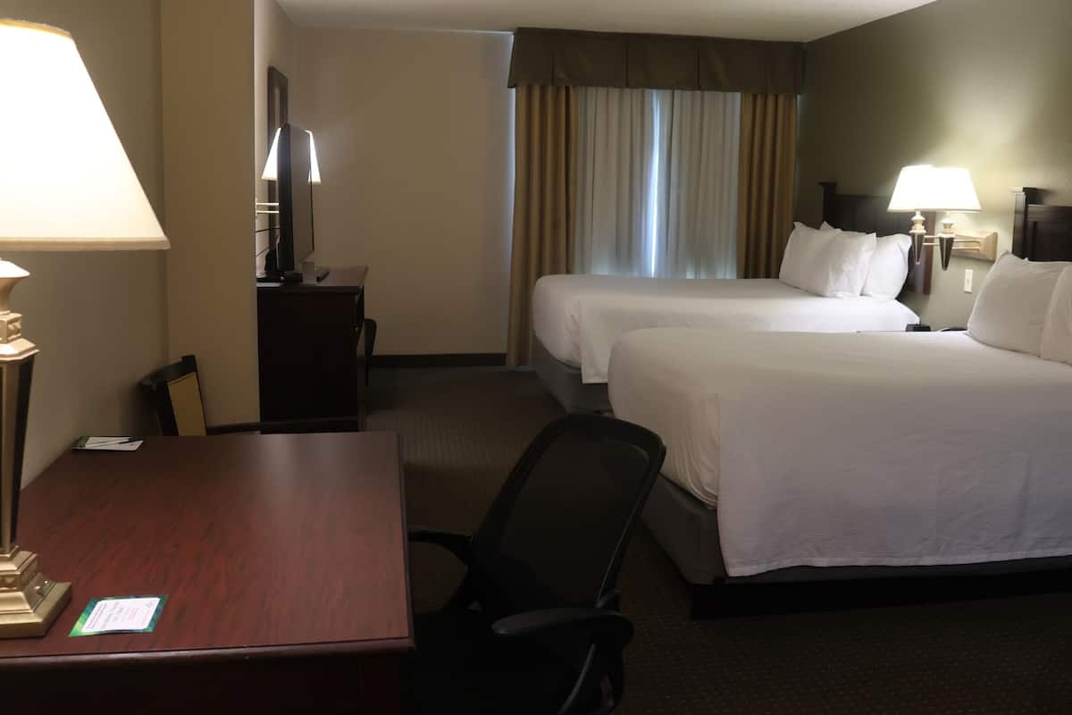 Une chambre d’hôtel avec deux lits, un bureau, une chaise et deux lampes.