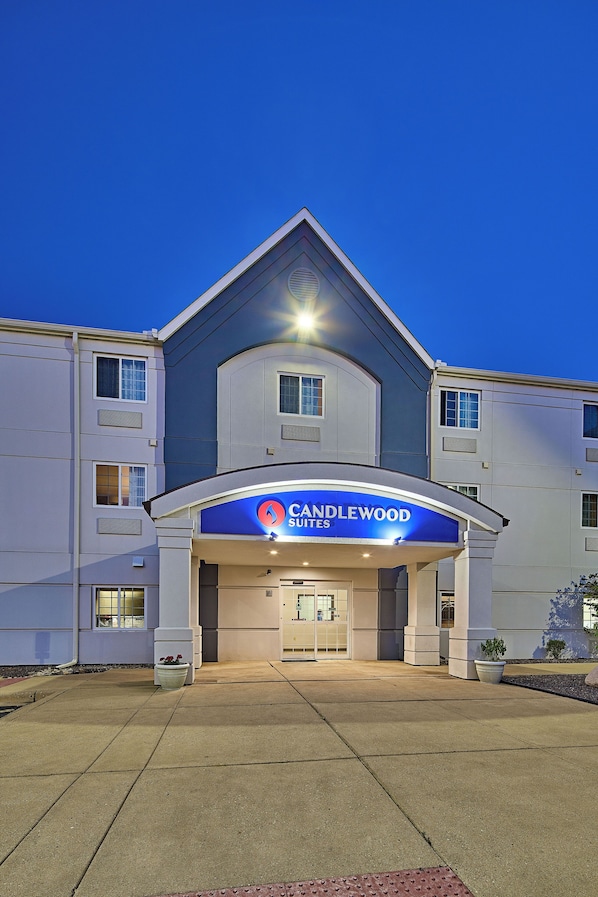 Entrada de um hotel com uma placa azul que diz 'Candlewood Suites'.