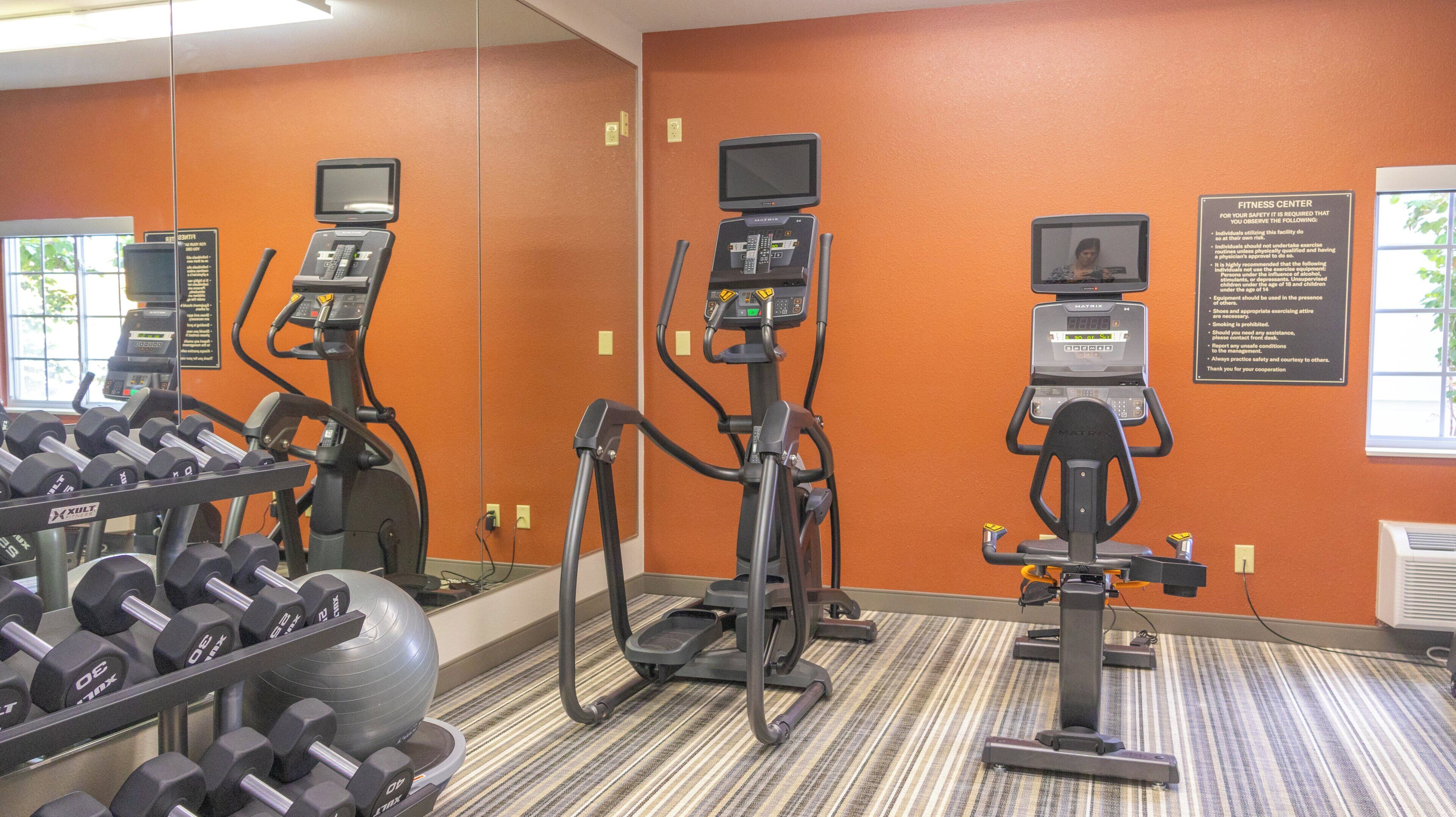 Un gimnasio con cintas de correr, elípticas y mancuernas.