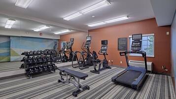 Ein Fitnessstudio mit Laufbändern, Crosstrainern und Kurzhanteln.