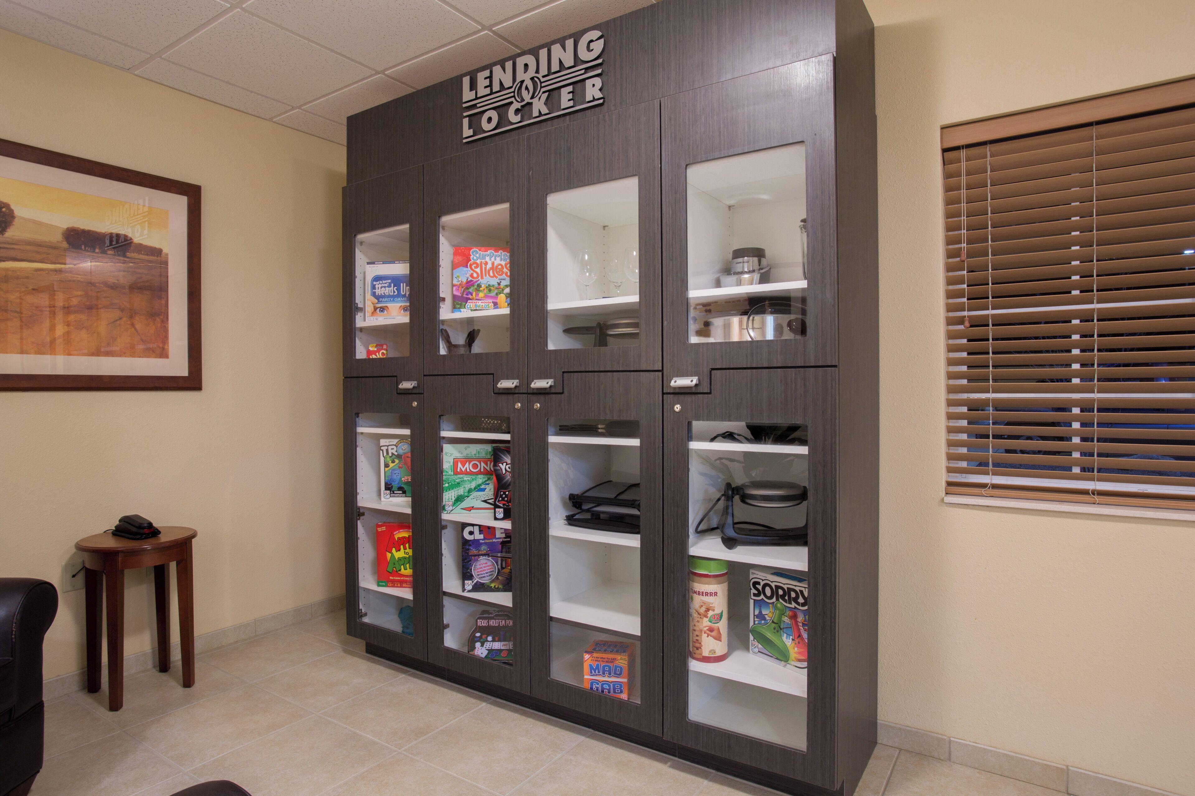 A lending locker with various board games and a framed picture on the wall.
