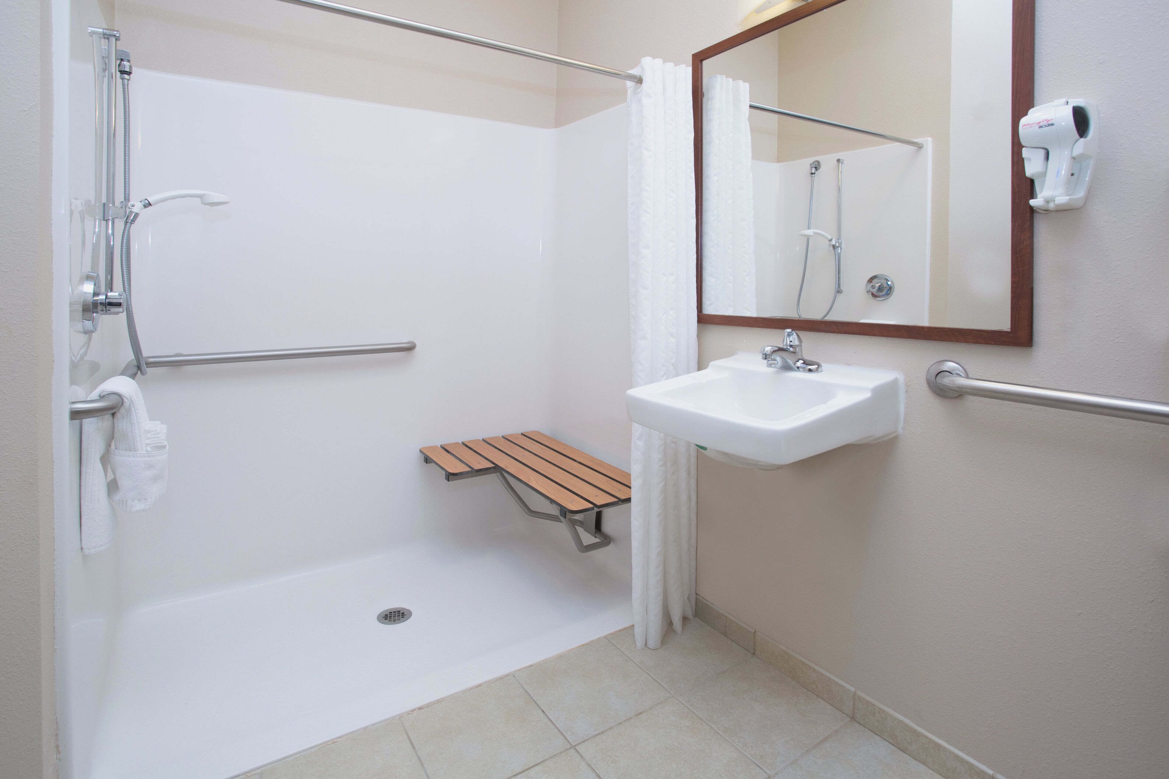 Une salle de bain avec une douche, un lavabo, un miroir et une étagère en bois.