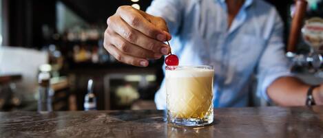 Eine Person serviert einen Cocktail mit einer Kirsche als Dekoration.