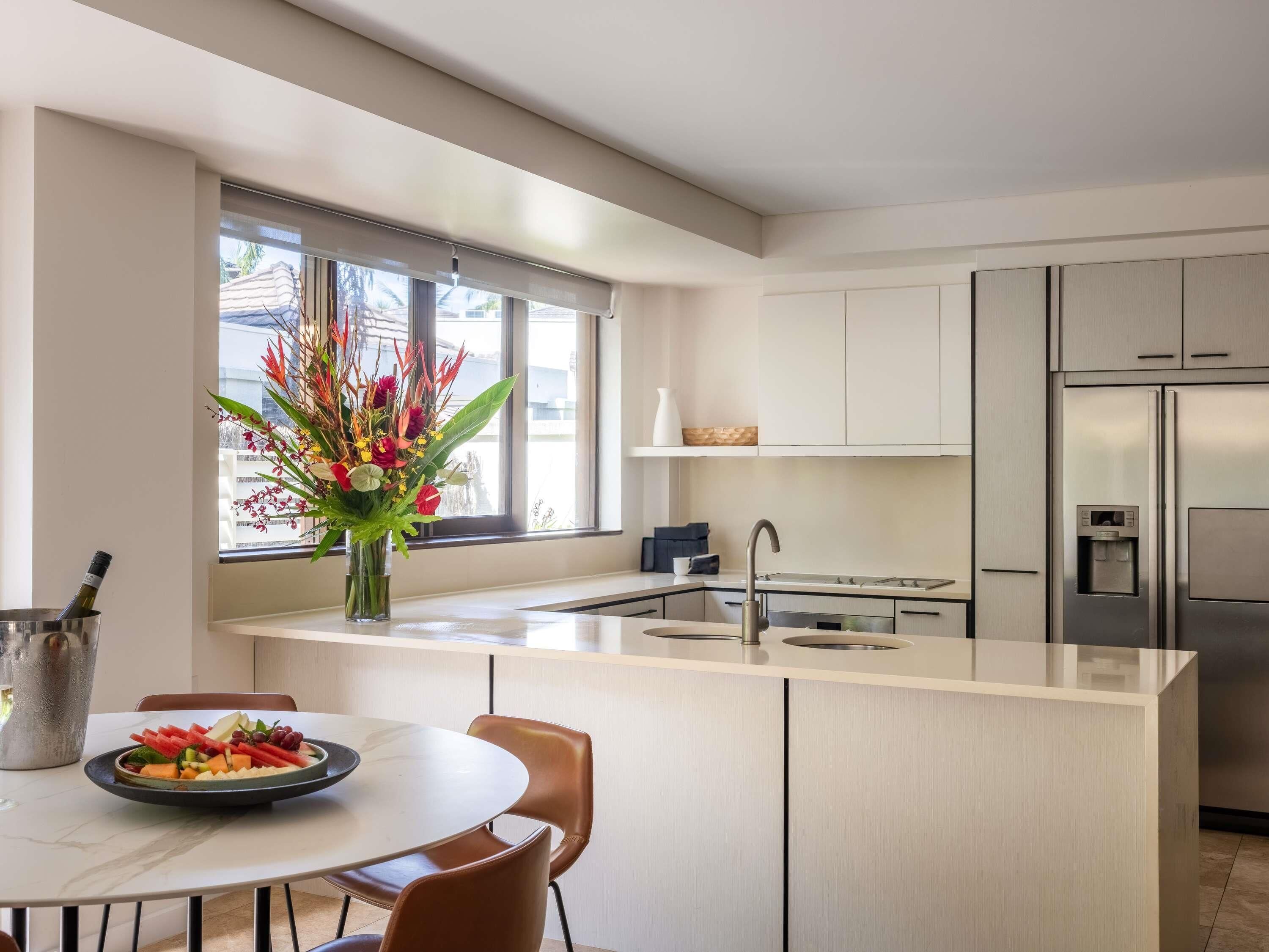 A modern kitchen with a central island, stainless steel appliances, and a dining area with a table and chairs.