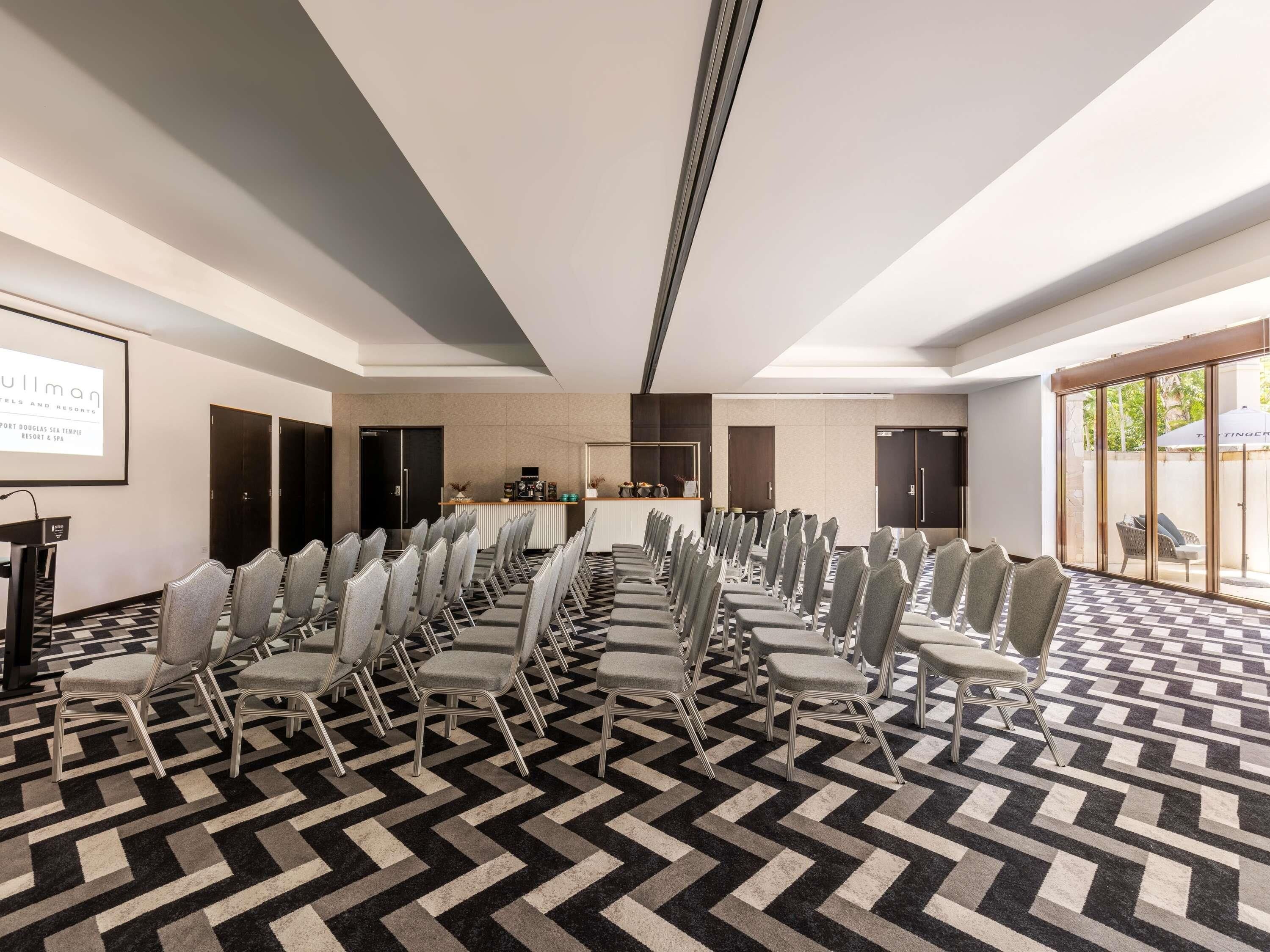 A conference room with rows of chairs, a podium, and a projection screen.