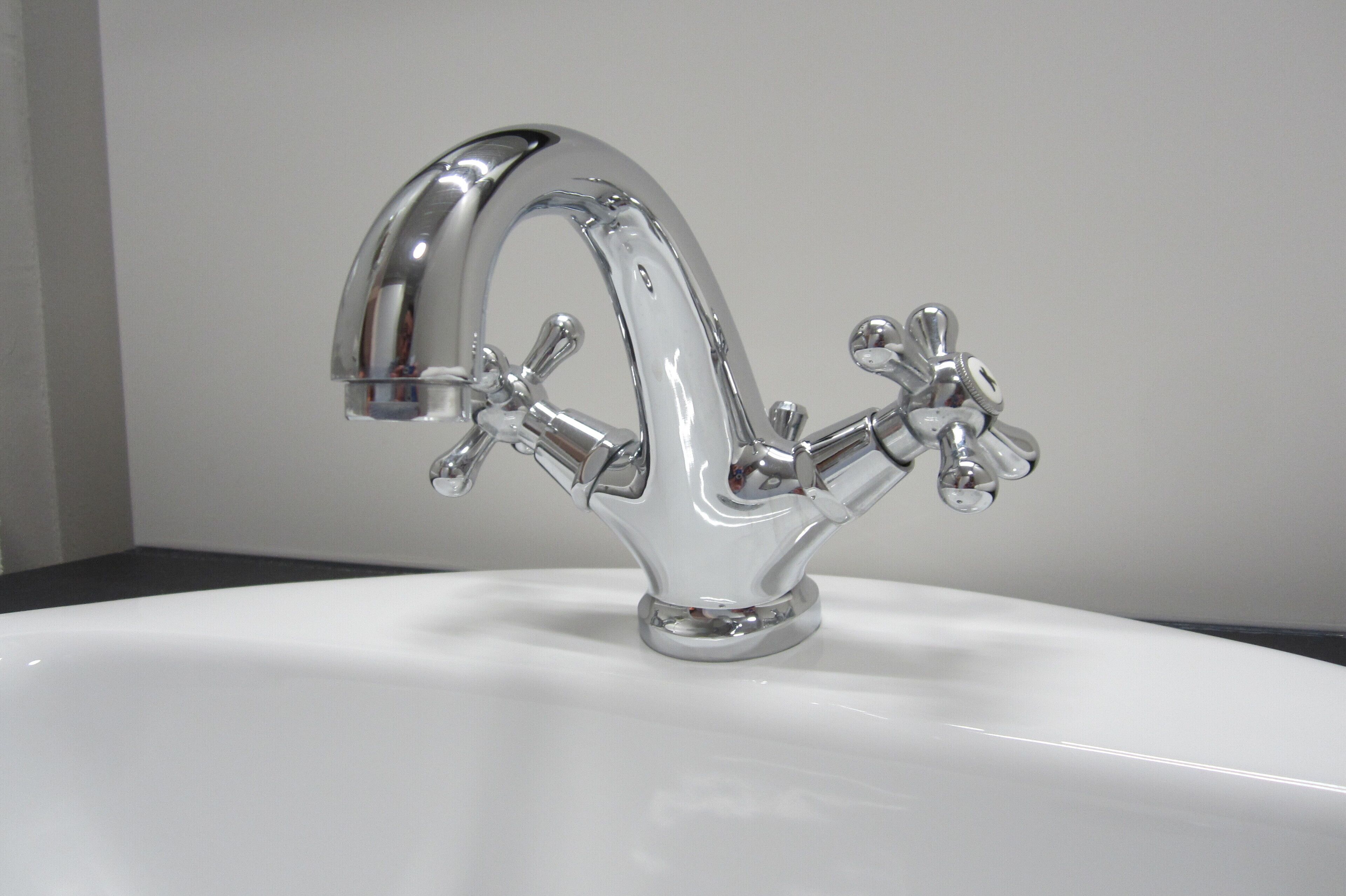 A chrome faucet with multiple handles on a white sink.