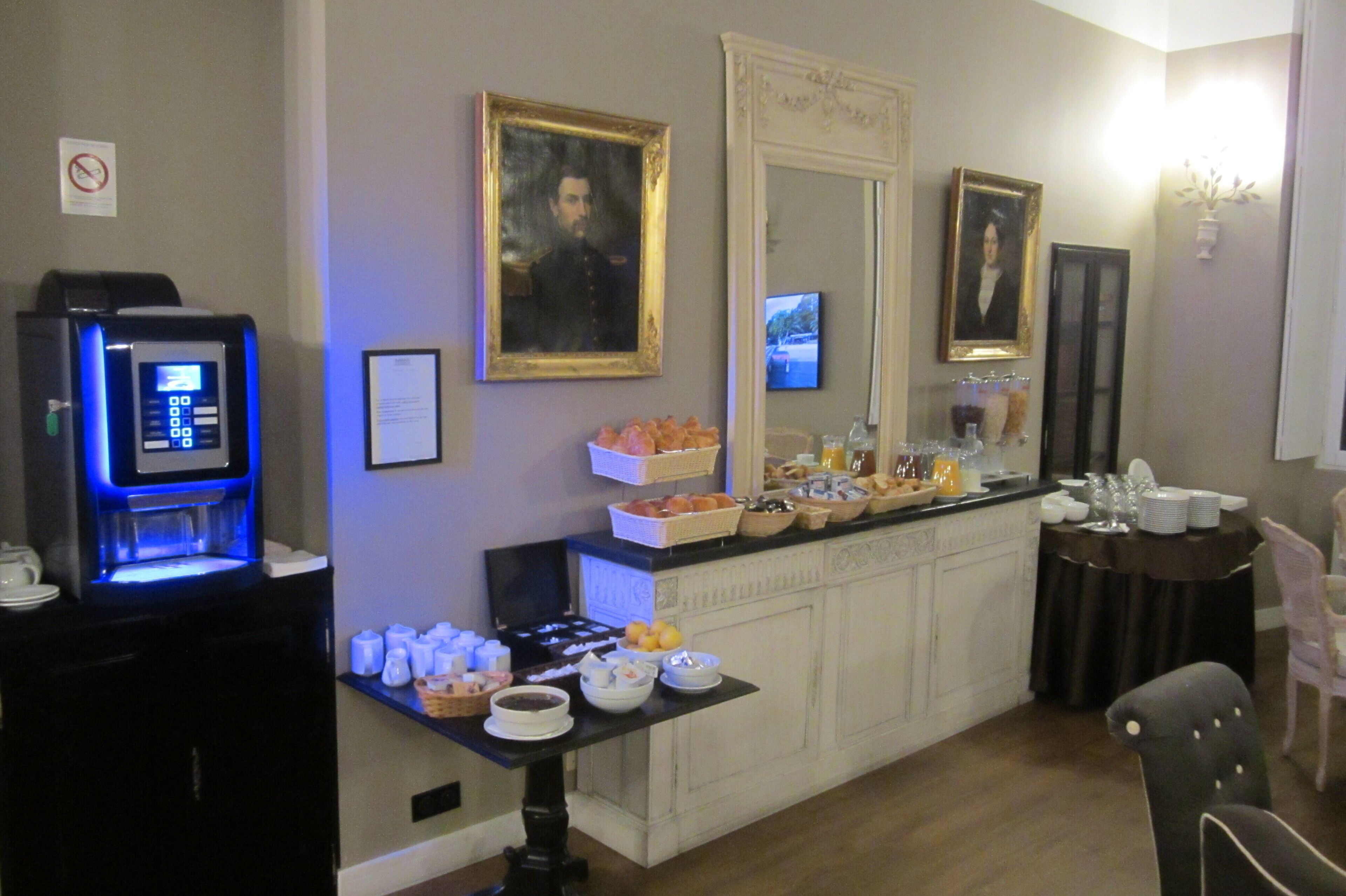 A hotel room with a minibar, a buffet table with breakfast items, and a television.