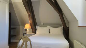 A bedroom with a bed, a nightstand, a lamp, and a chair.