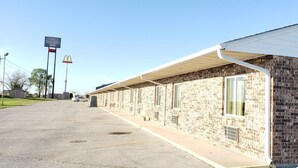 Un motel con fachada de ladrillo, un corredor cubierto y un estacionamiento.