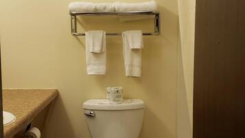 A small bathroom with a toilet, a towel rack with two towels, and a shower curtain.