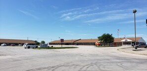 A parking lot with a building labeled "Antiques" and a flagpole with an American flag. - Family Budget Inn Bethany (Bethany)