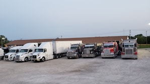Una fila de camiones estacionados en un estacionamiento de grava.