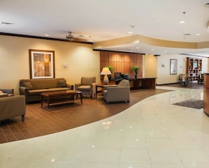 Um hall amplo com balcão de recepção, área de estar e uma grande obra de arte emoldurada na parede.