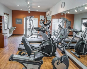 Centro de fitness com equipamentos de cardio, máquinas de peso e um espelho grande.