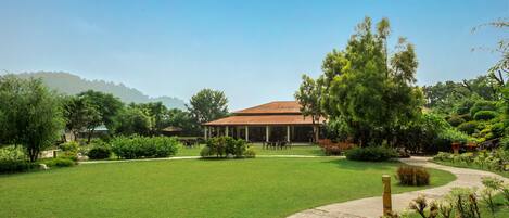 A spacious lawn with a curved pathway leading to a building with a red roof.