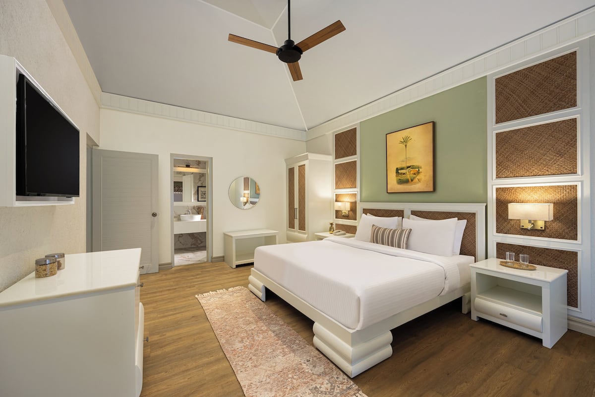 A modern bedroom with a large bed, bedside tables, a ceiling fan, and a television.