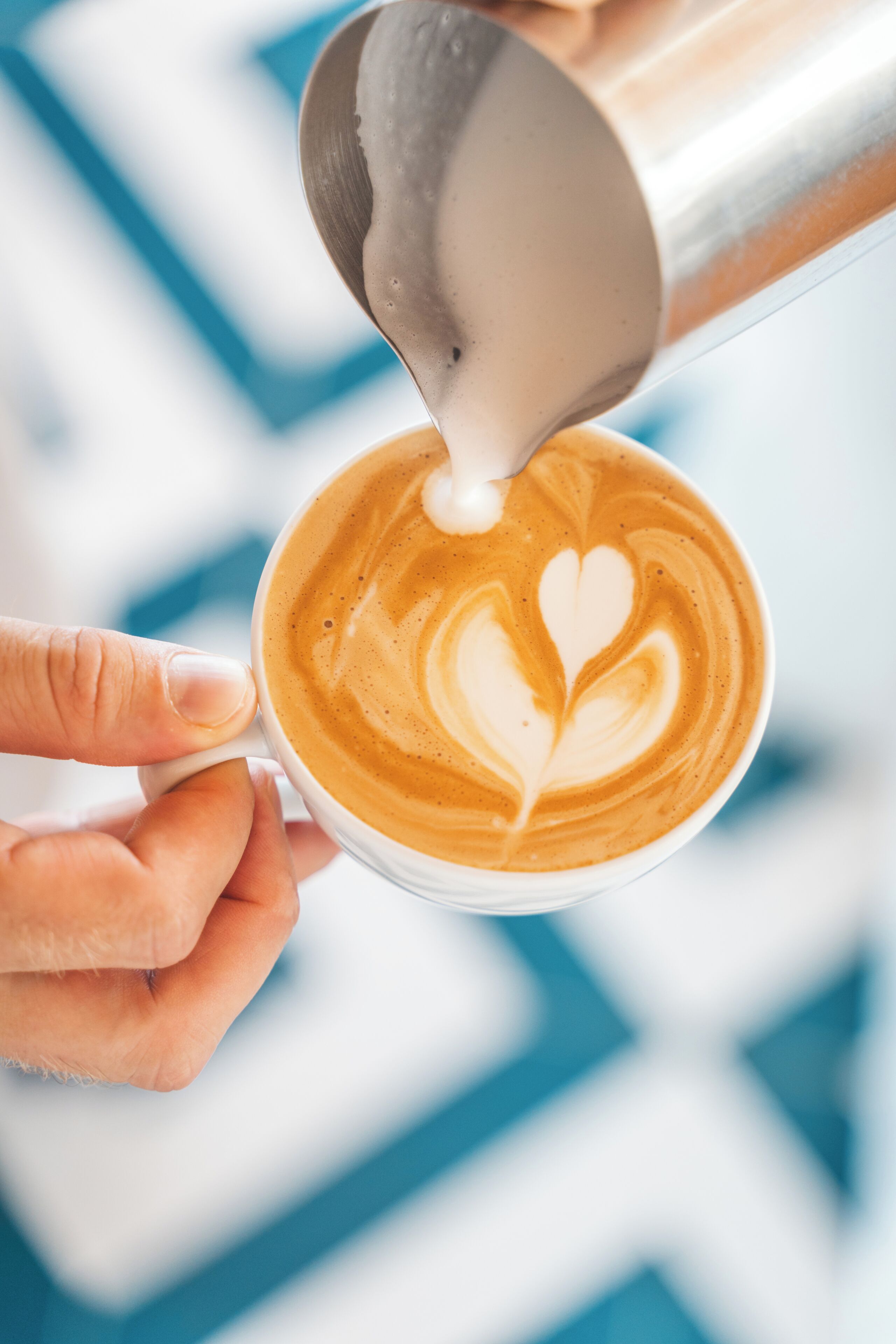 A hand holding a cup of coffee with latte art.