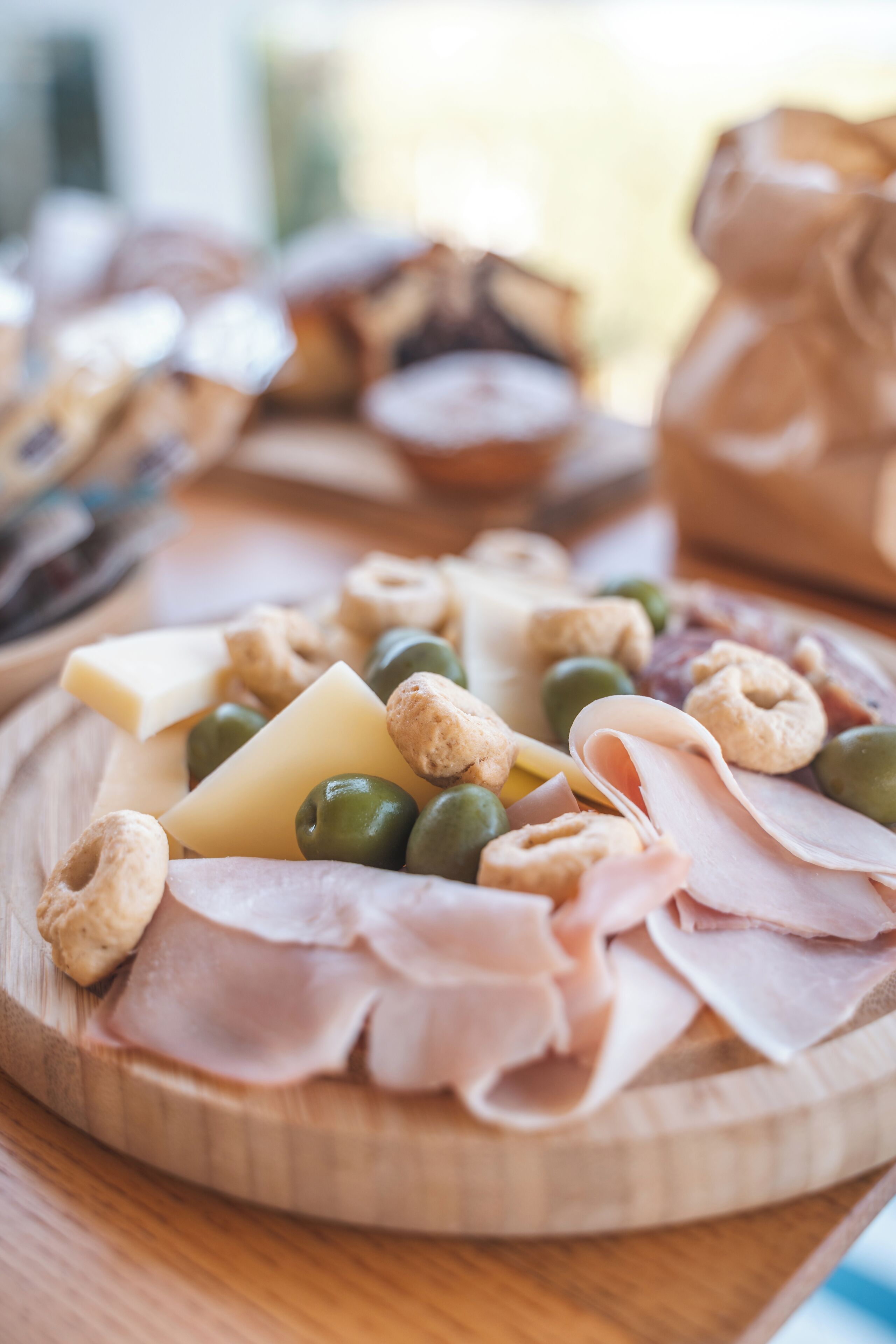 Une planche en bois garnie de différents fromages, d’olives, de noix et de charcuteries.