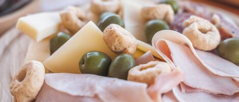 A wooden board with various cheeses, olives, nuts, and sliced meats.