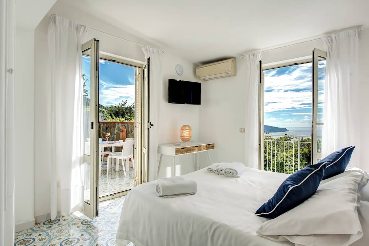 Ein Hotelzimmer mit Bett, Schreibtisch, Fernseher und einem Balkon mit Blick.