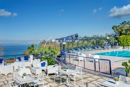 Una piscina al aire libre, sombrillas, sillones reclinables de piscina