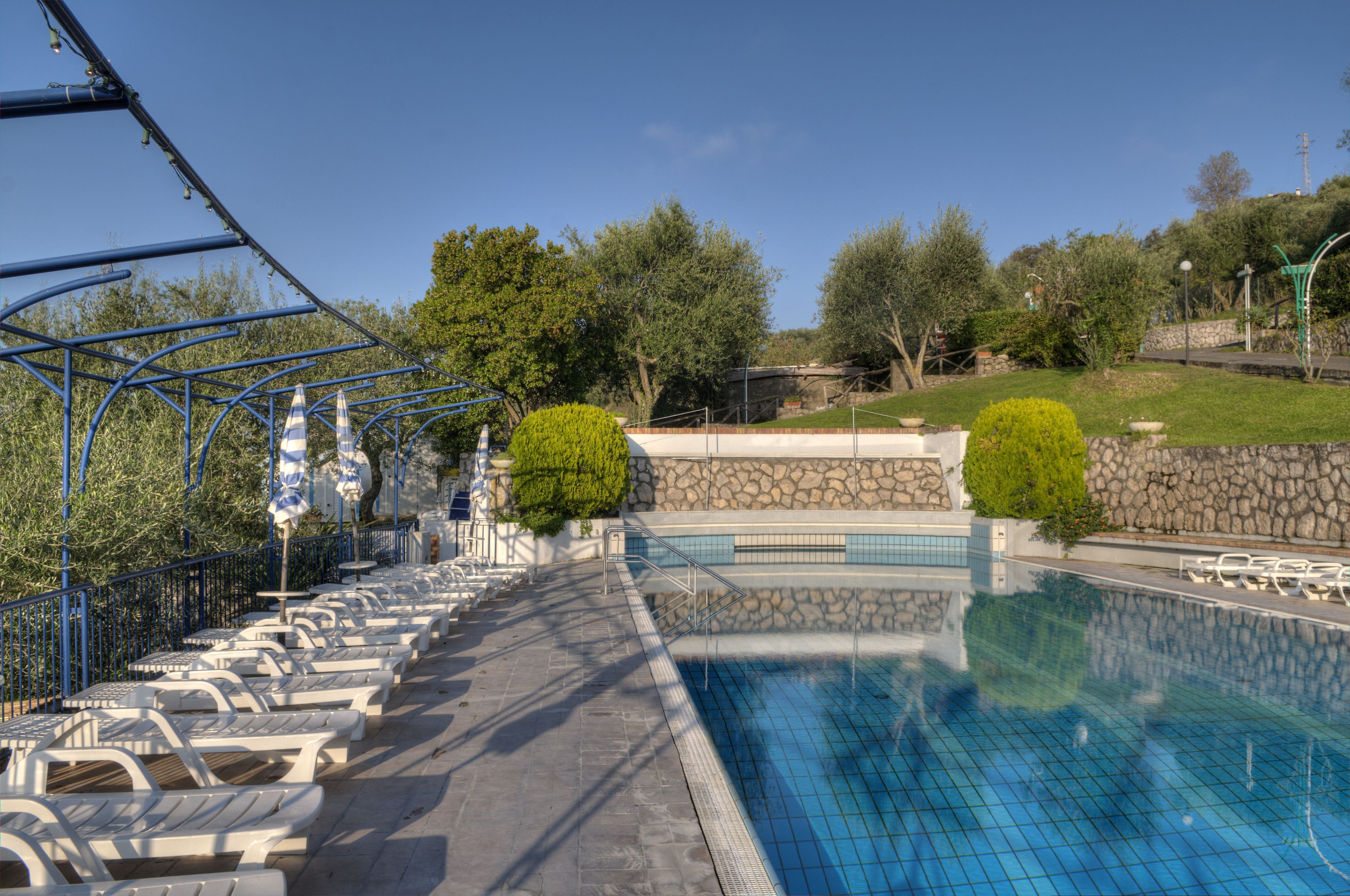 A swimming pool with lounge chairs and a stone wall.