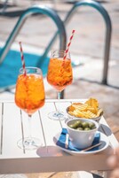 Una mesa con dos bebidas, un tazón de papas fritas y un tazón de aceitunas.