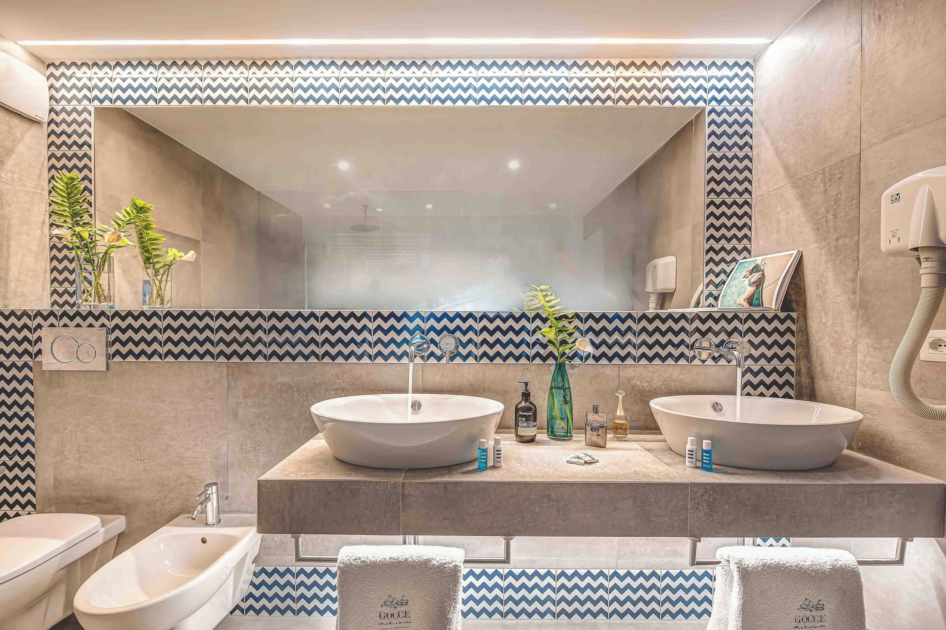 Un baño con dos lavamanos, un espejo y un perchero para toallas.
