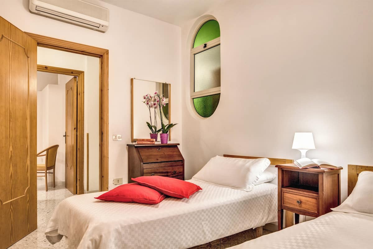 Ein Schlafzimmer mit zwei Betten, einem hölzernen Schminktisch, einem Spiegel, einem Fenster und einem Stuhl.