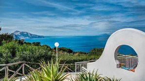 A white building with a balcony overlooking a coastal view.