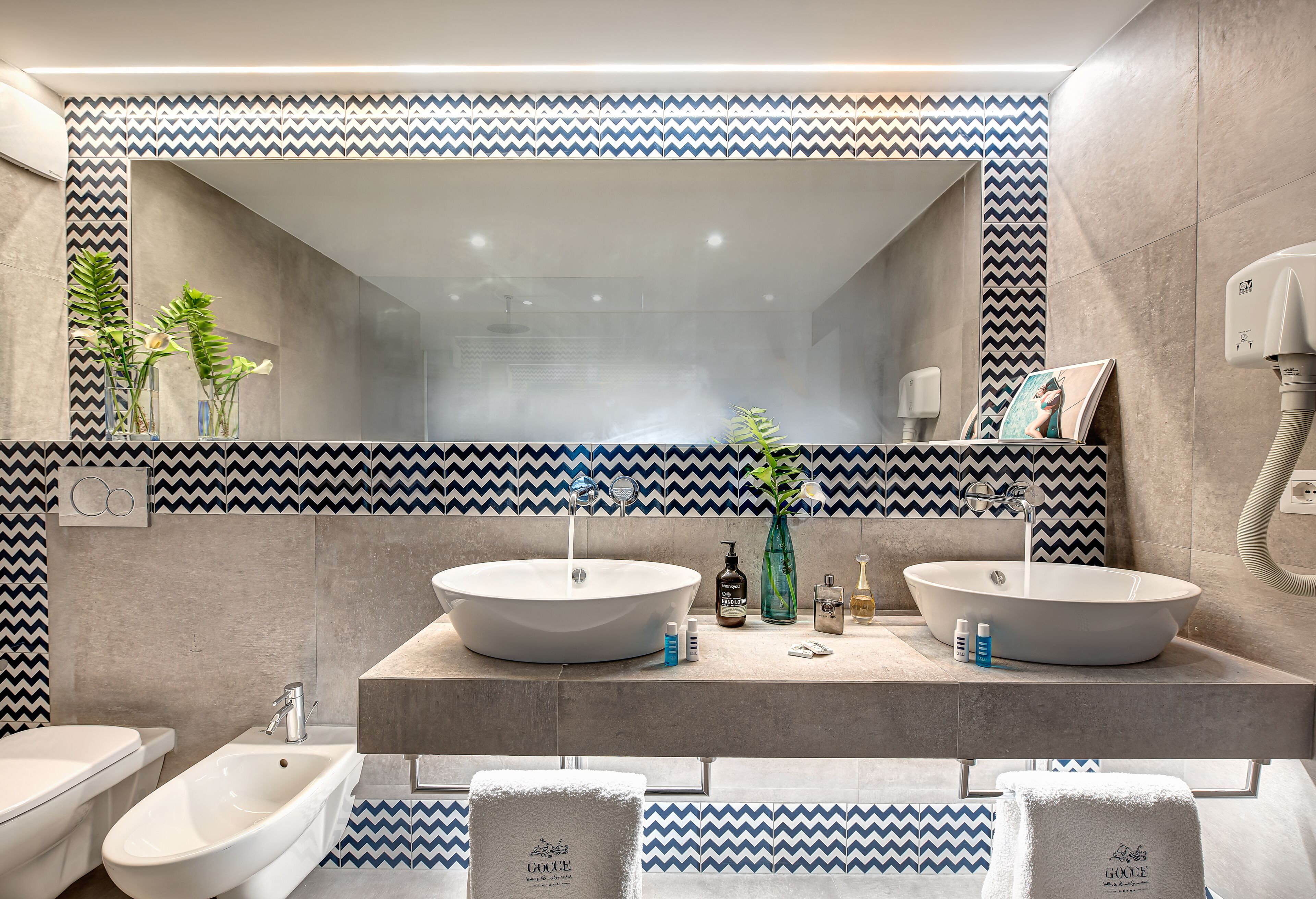 A modern bathroom with two sinks, a bidet, and a large mirror.