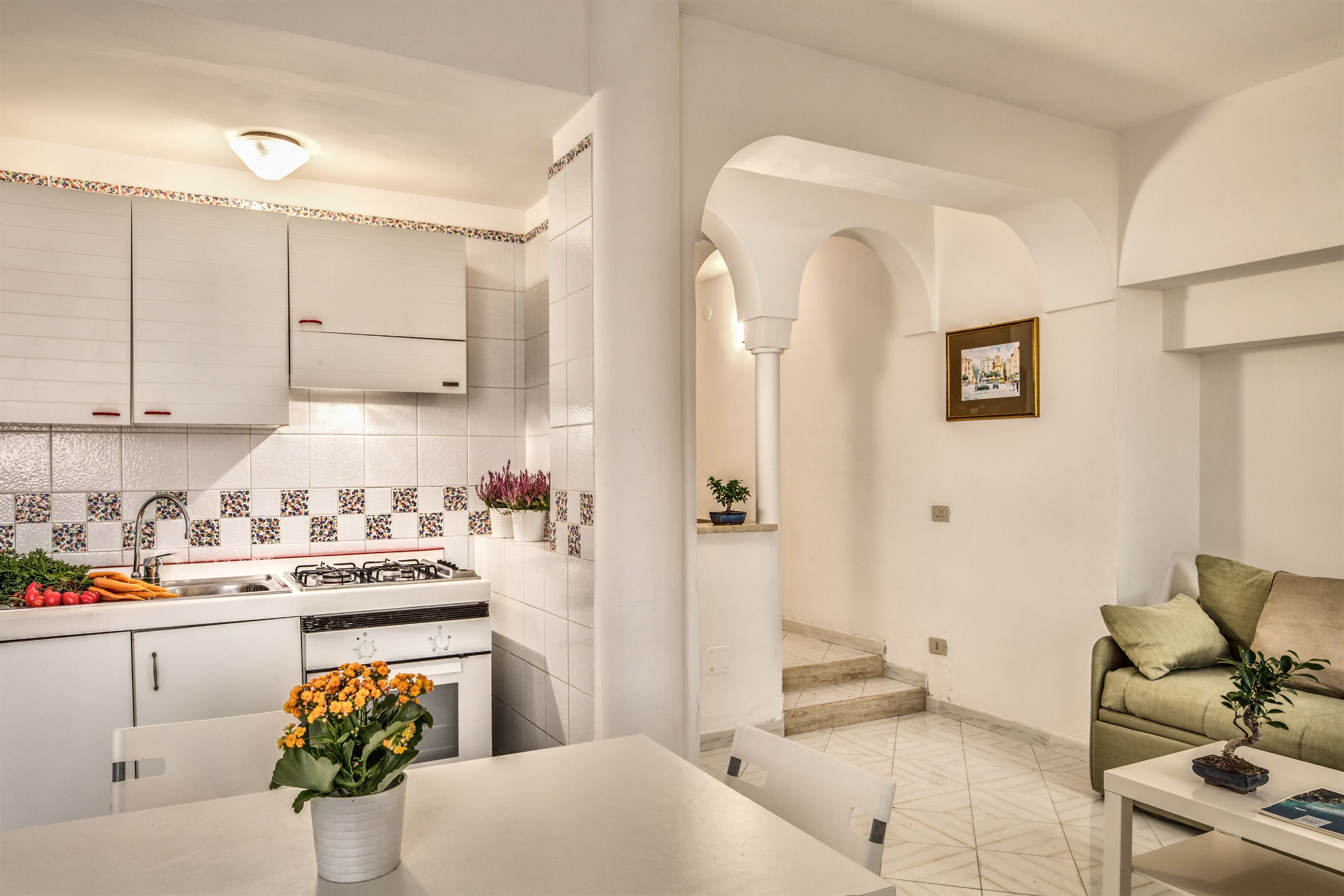 A modern kitchen with white cabinets, a tiled backsplash, and a dining area with a white table and chairs.