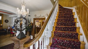 Una imponente escalera con alfombra roja que conduce a una zona de recepción.