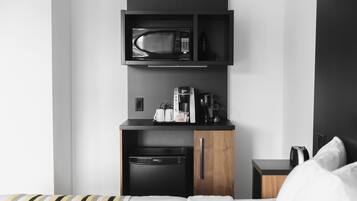 A compact kitchenette with a microwave, coffee maker, and toaster.