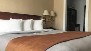 A hotel room with a large bed, two bedside lamps, a telephone, and a wardrobe.