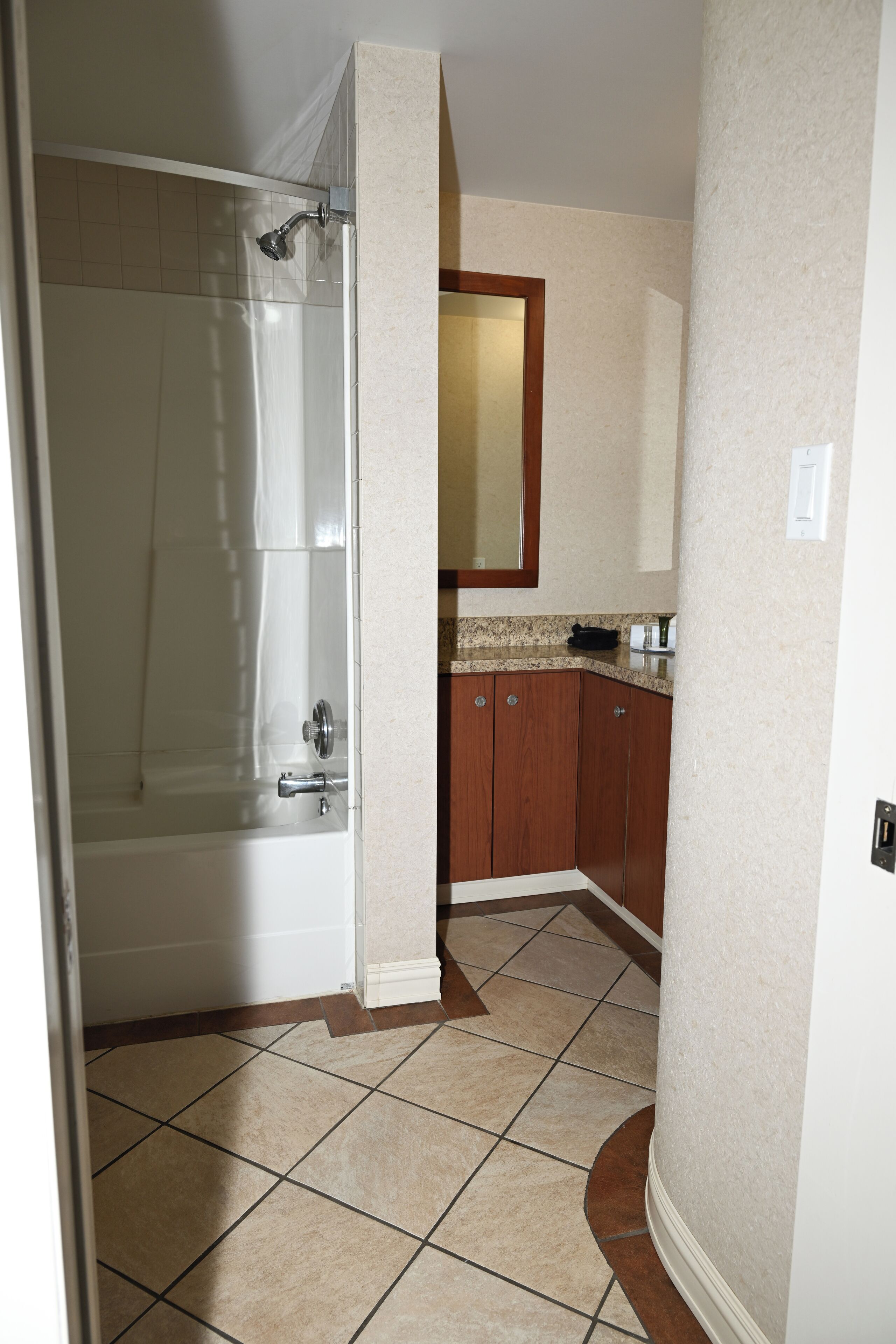 Un baño con ducha, lavamanos y armarios de madera.