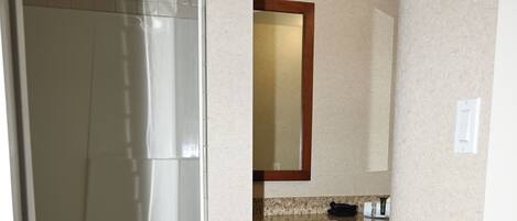 Un baño con ducha, lavamanos y armarios de madera.
