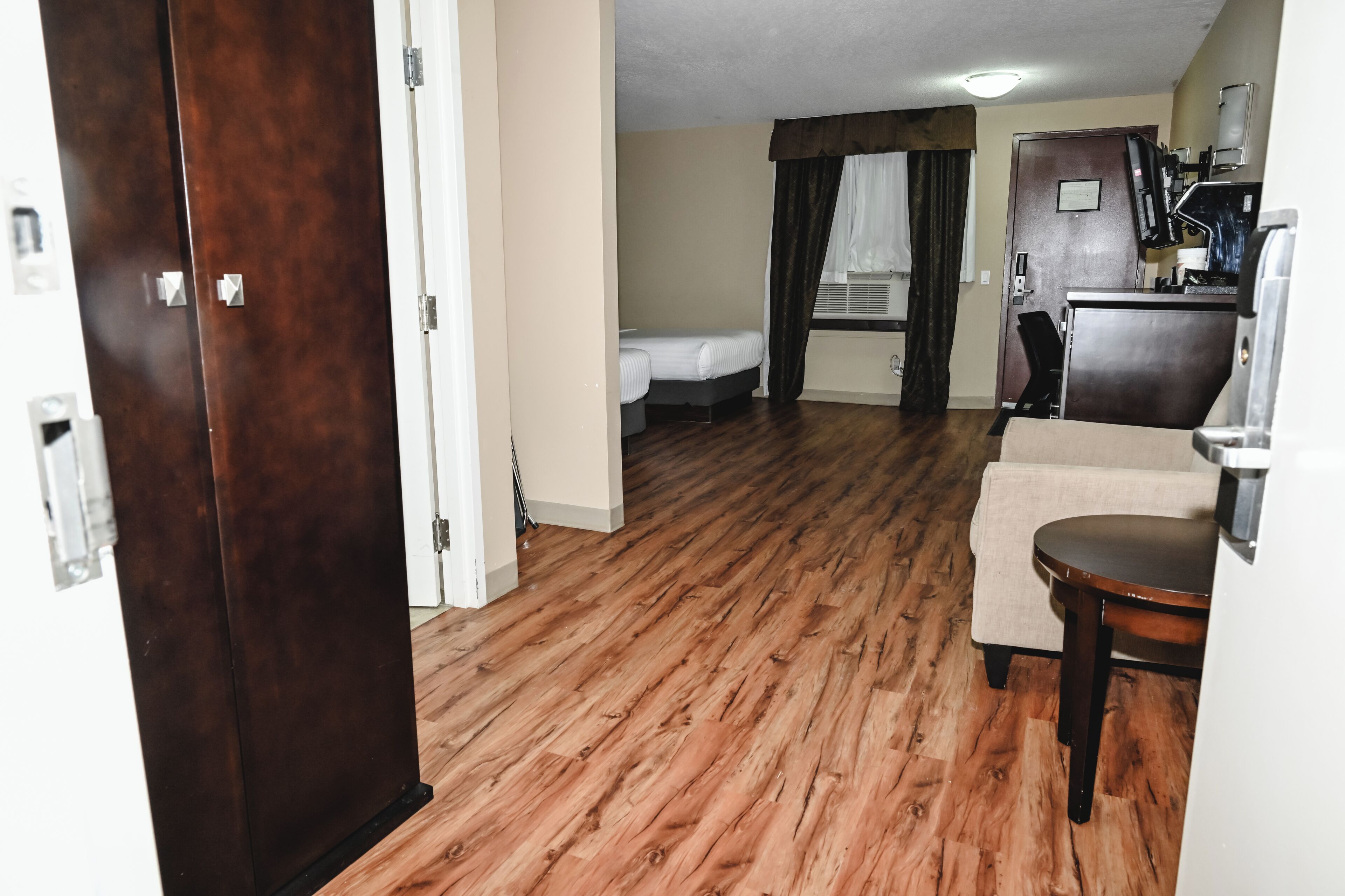 Una habitación de hotel con piso de madera, una cama, un escritorio y una silla.
