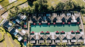 An aerial view of a resort with multiple bungalow-style accommodations, a central swimming pool, and surrounding landscaped areas. - FuramaXclusive Resort & Villas, Ubud (Mas)