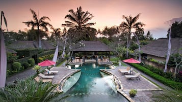 Una piscina al aire libre, sombrillas, tumbonas