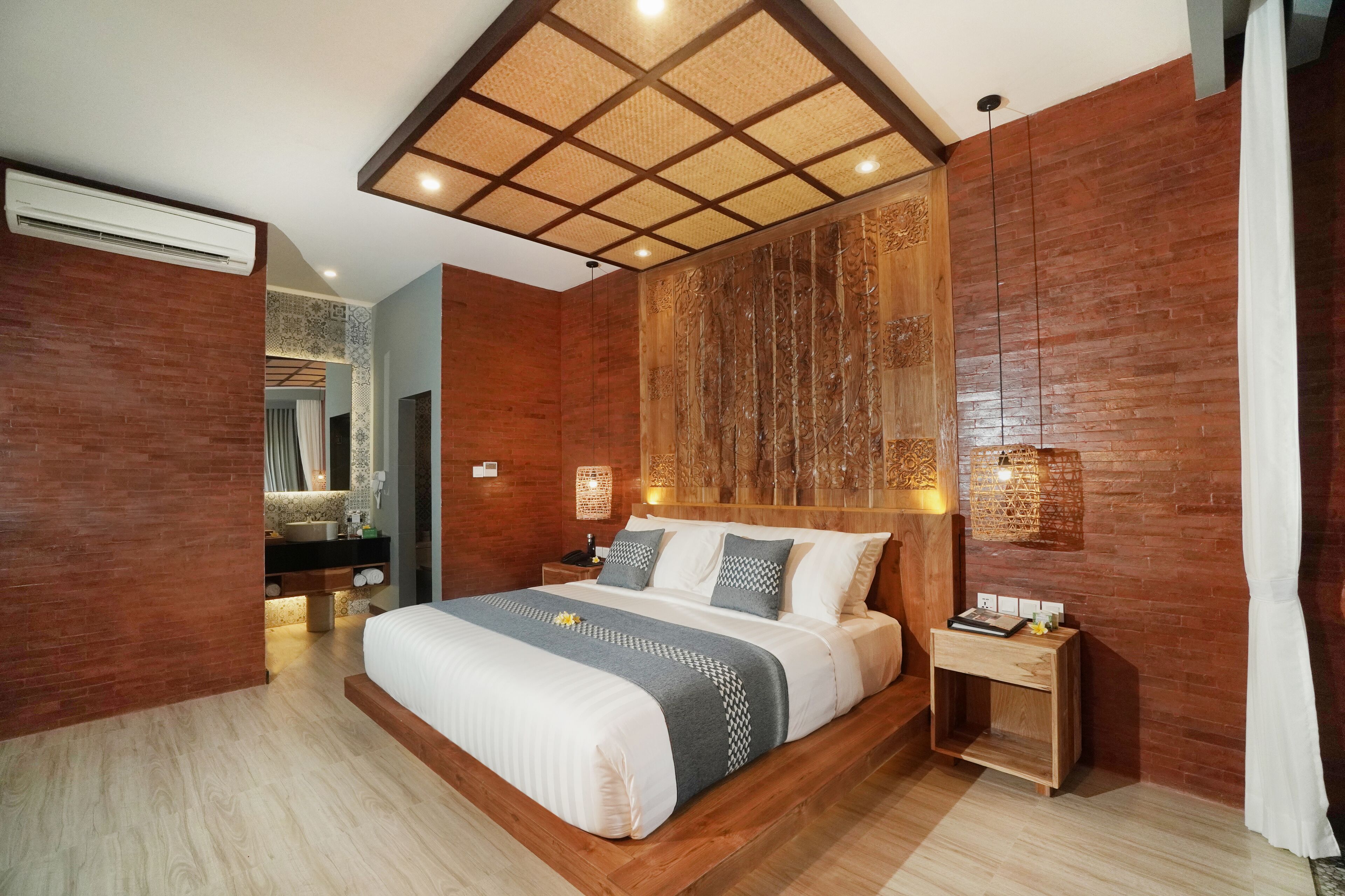 A modern bedroom with a large bed, wooden paneling, a nightstand, and a wall-mounted light fixture.