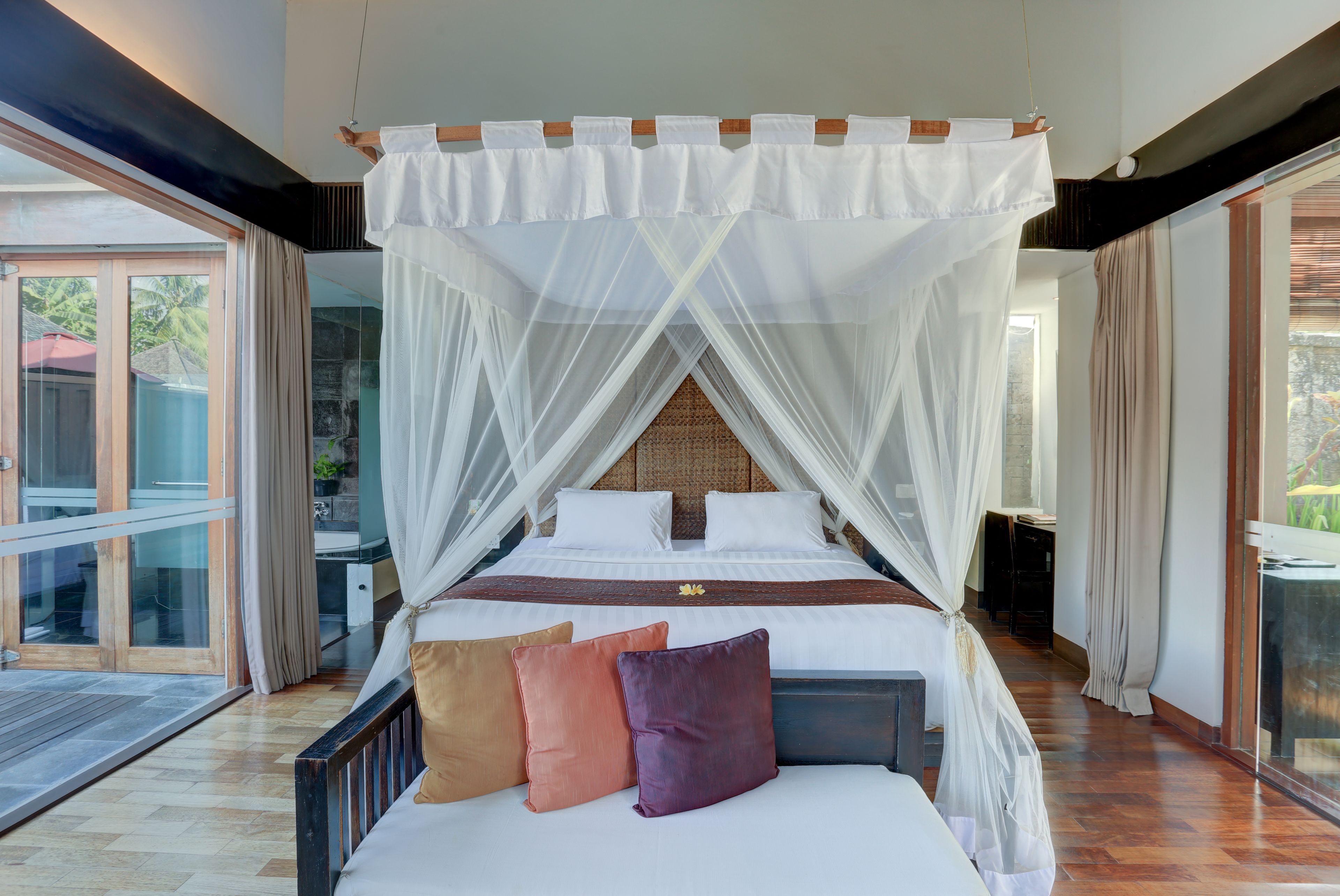 A four-poster canopy bed with white bedding and a wooden headboard.
