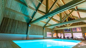 An indoor swimming pool with wooden beams and tiled walls.