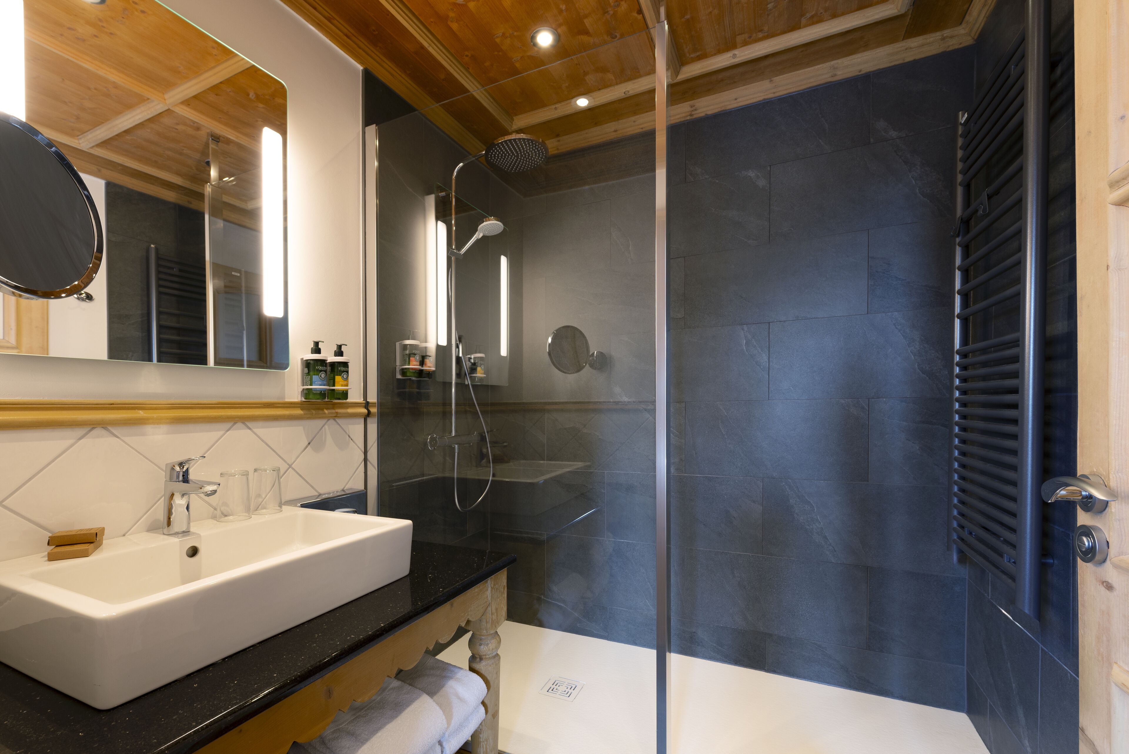 Un bagno moderno con uno specchio grande, un lavandino bianco e una cabina doccia in vetro.