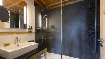 Un bagno moderno con uno specchio grande, un lavandino bianco e una cabina doccia in vetro.