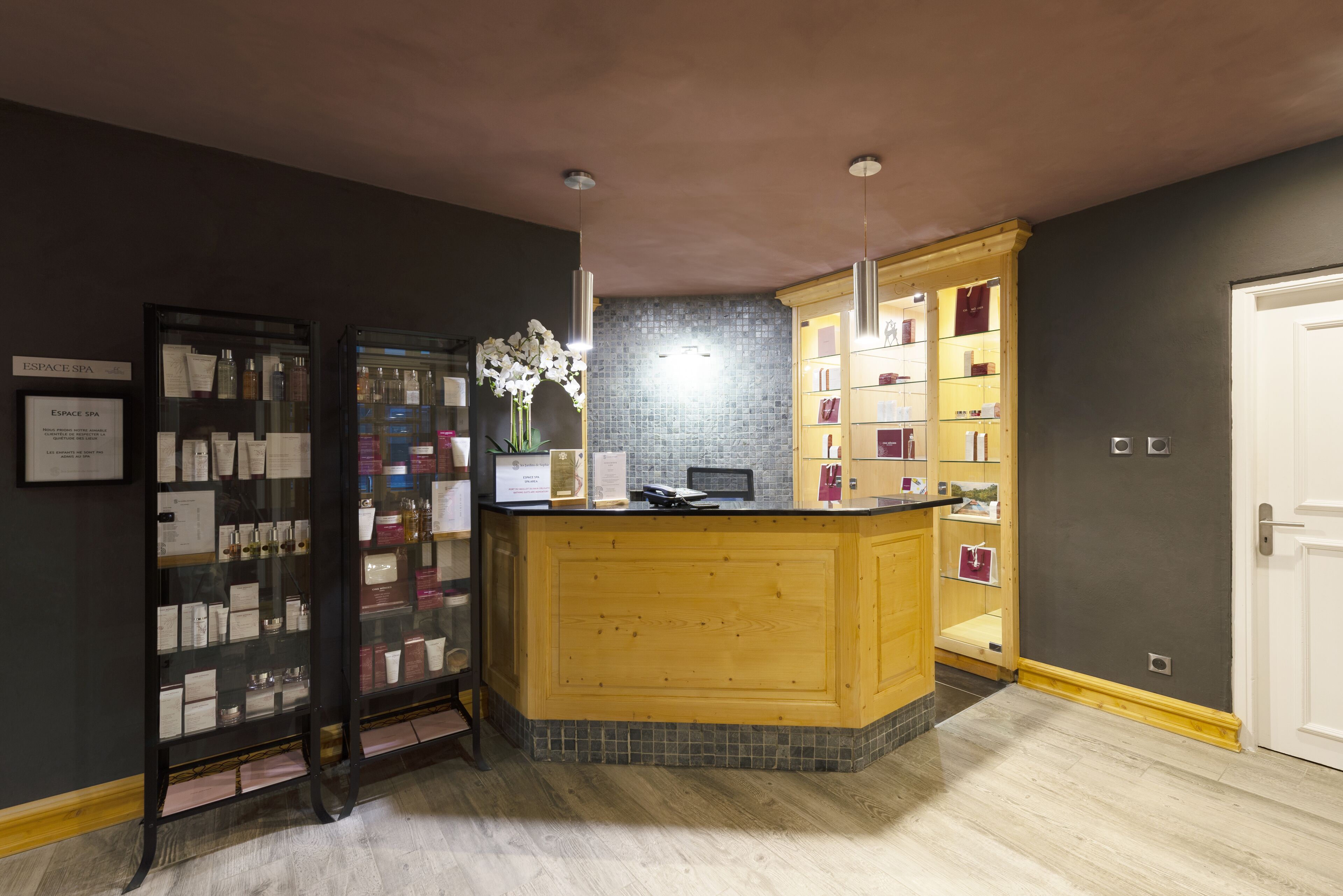 A reception area with a wooden counter, a glass display case, and a tiled backsplash.
