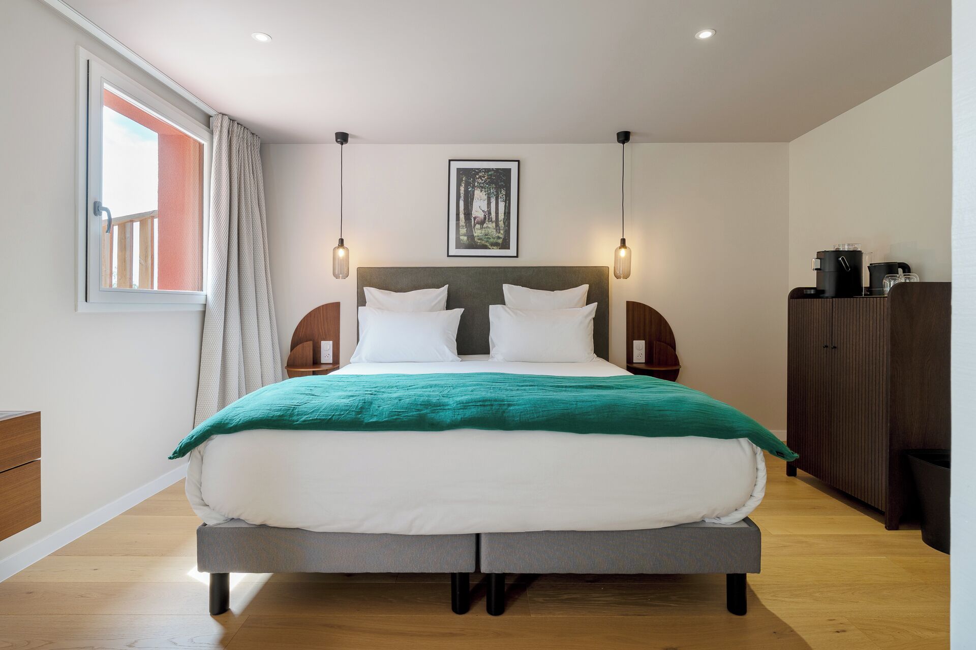 Een moderne hotelkamer met een groot bed, uitzicht op de omgeving en een houten vloer.