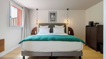 Een moderne hotelkamer met een groot bed, uitzicht op de omgeving en een houten vloer.